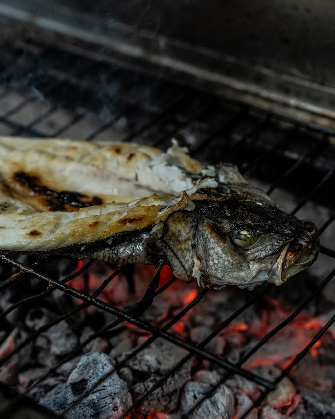 Pescado abierto sobre la parrilla de carbón